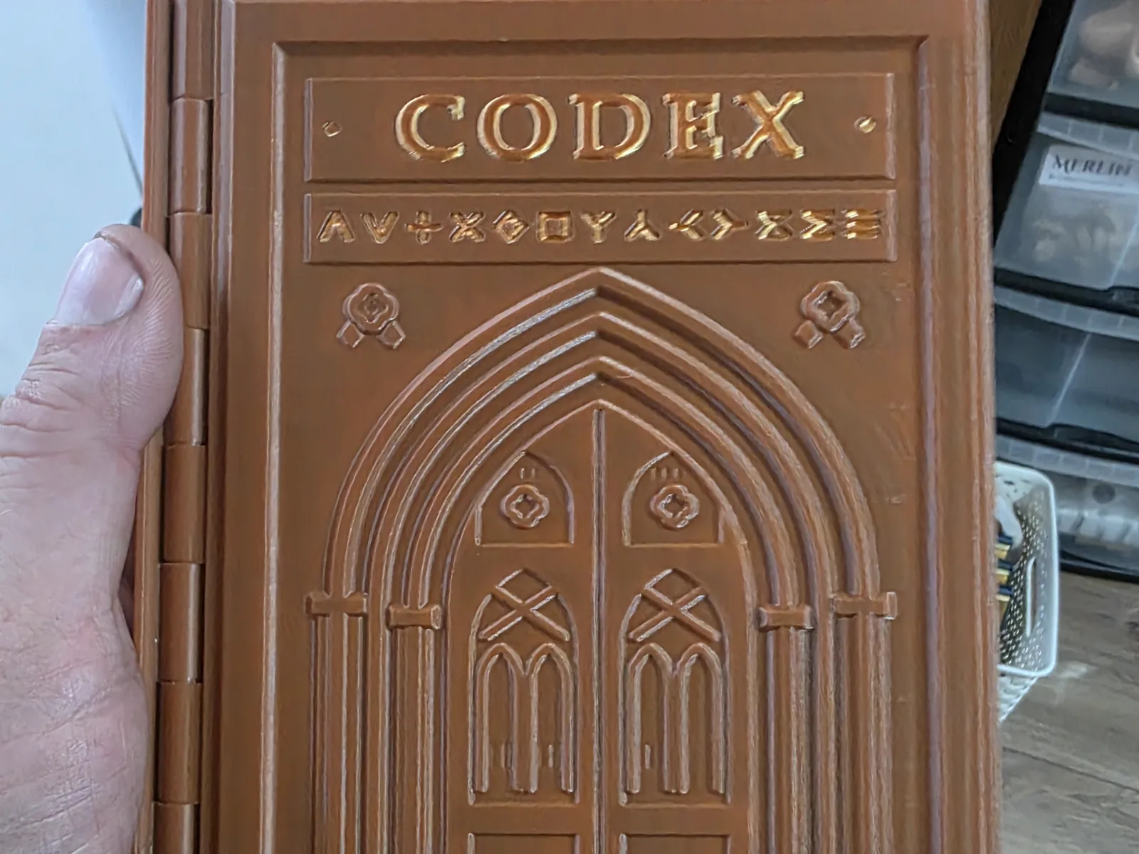 Brown and gold 3D-printed Codex prototype held in one hand.